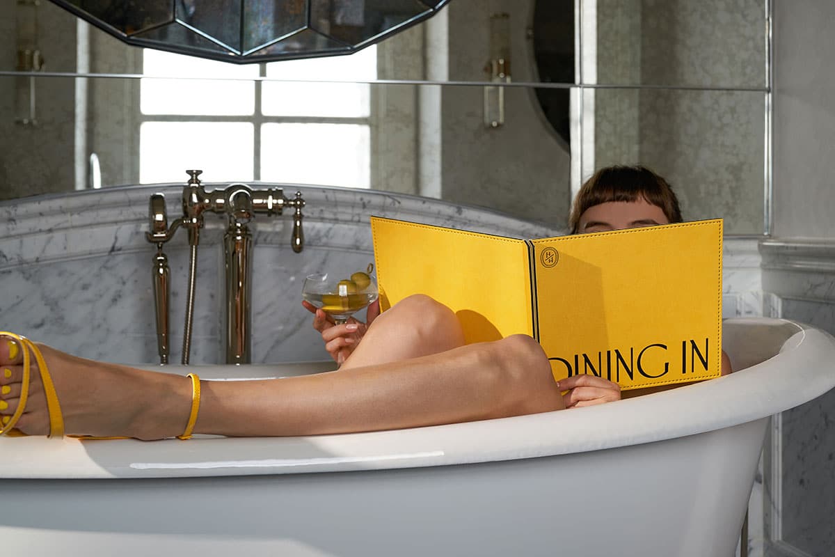 Eine Frau, die in einer Badewanne ein gelbes Menü liest