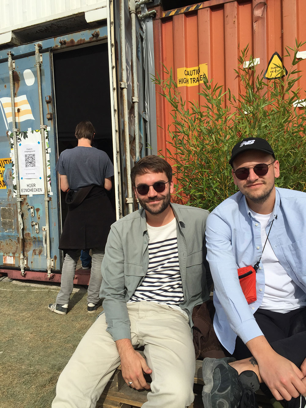 Christian Nicolaus und Felix Bareis sitzen vor dem Container