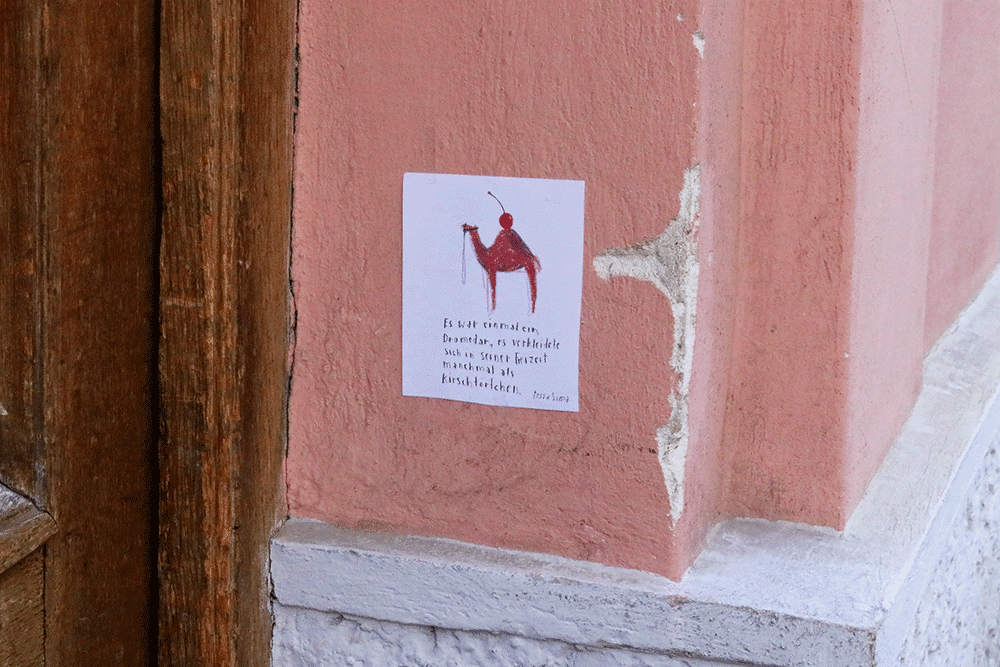 Einblatt Geschichte Kamel an Hauswand