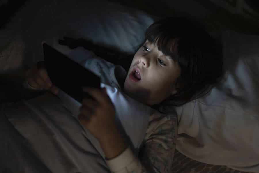 Stockfotos Kind mit Handy im Bett