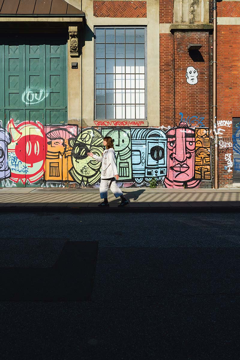 Frau geht vor Wand mit Grafitti entlang