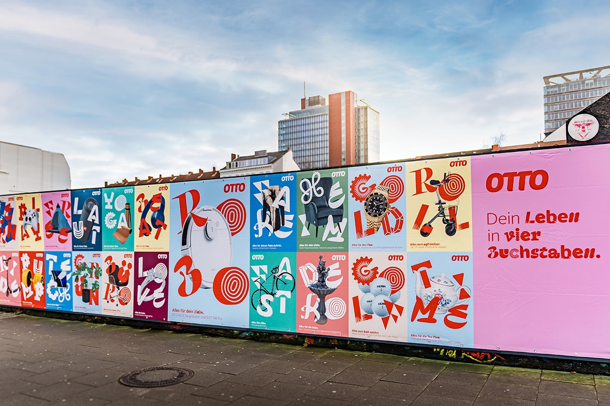 Bunte Plakate an einem Bauzaun vor Hamburger Hochhäusern und blauem Himmel