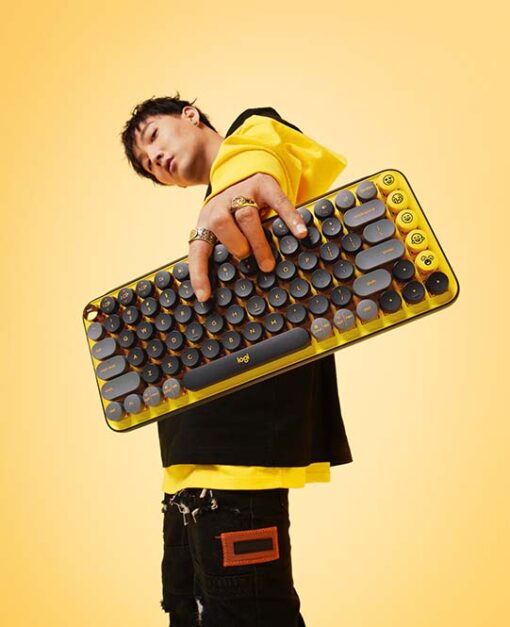 Gelb gekleideter Mann hält gelbe POP Key Tastatur in die Kamera