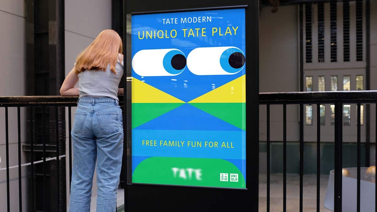 Frau steht neben digitalem Plakat, das die Kampagne für das Uniqlo Tate Play Programm zeigt