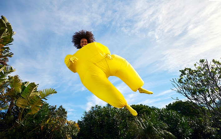 Eine Frau im gelben Anzug fliegt vor blauem Himmel