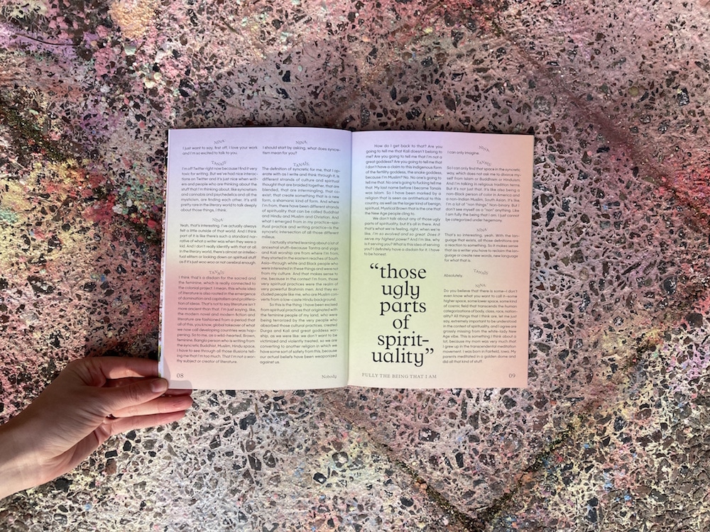 Aufgeschlagenes Nobody Magazin mit Textbeispiel auf Plastersteinen, die in zarten Regenbogenfarben bemalt sind