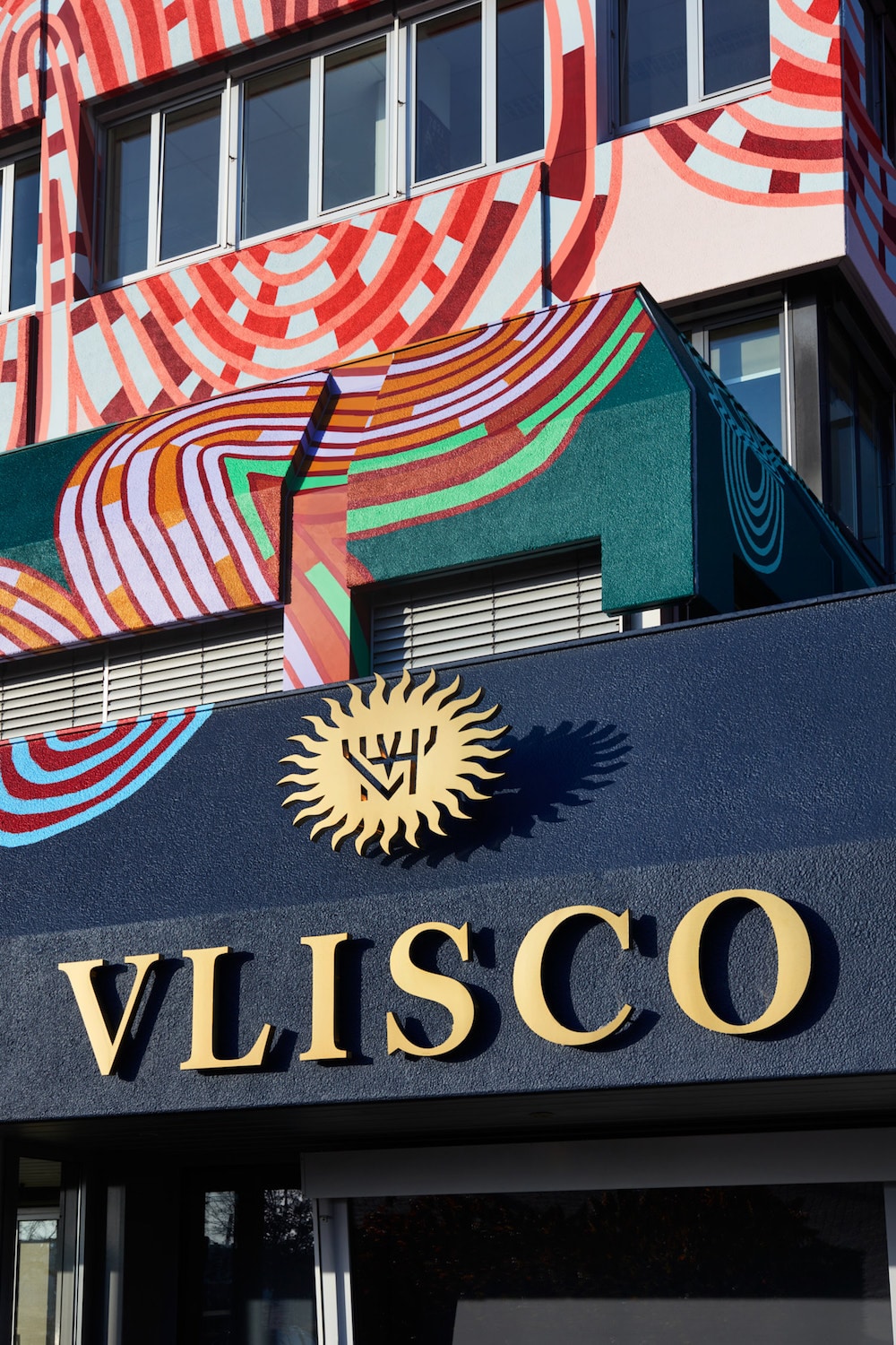 Mit bunten Wax-Print-Mustern überzogene Hausfassade des Stoffherstellers Vlisco, gestaltet von Simone Post, Eingang mit Logo