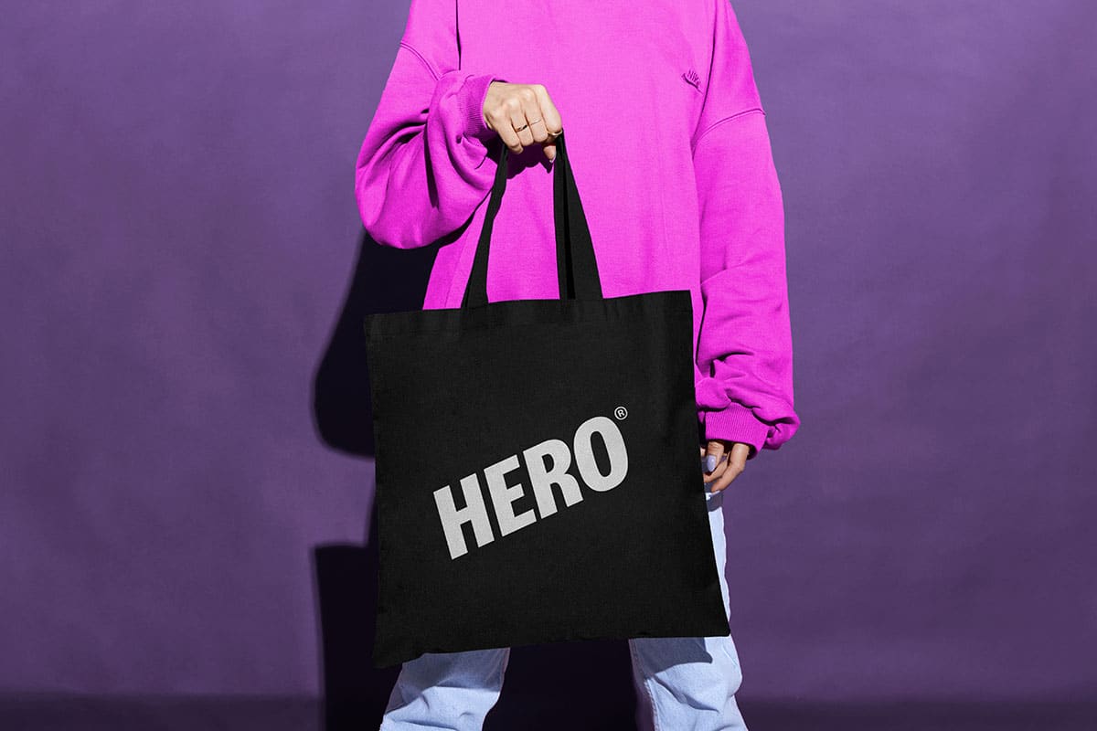 ein Mensch hält eine schwarze Tasche mit dem Hero Logo in die Kamera