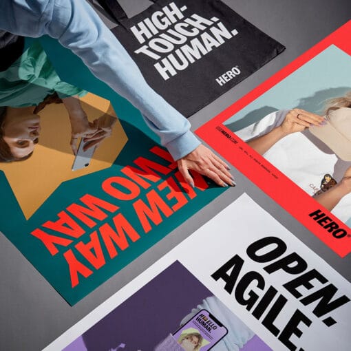 Eine Hand greift zwischen vier Plakate in leuchtenden Farben mit kursiver Typografie