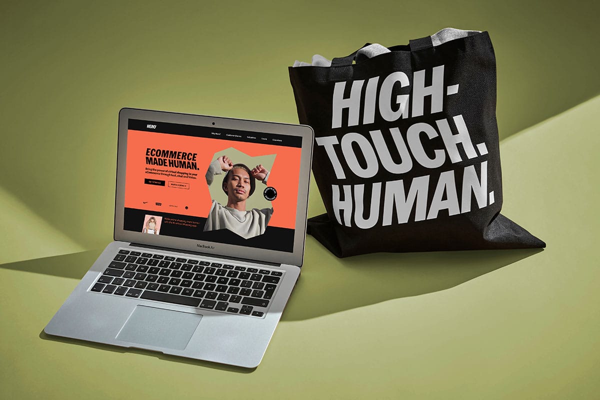Die Hero Website auf einem Laptop. Daneben steht eine Tasche mit dem neuen Claim der Marke: »High Touch. Human«