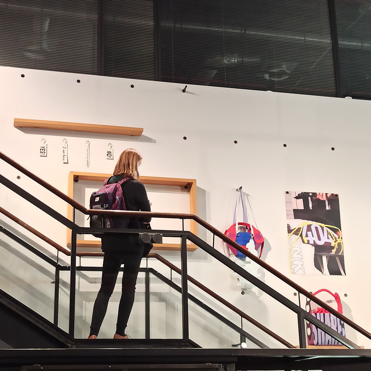 Eine Frau steht an einem Treppengeländer und betrachtet die Ausstellung