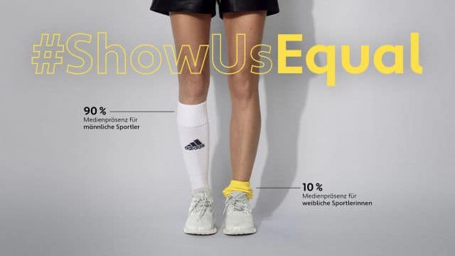 Zwei Socken werden auf ungleicher höhe getragen, um auf Ungleichgewicht und er Berichterstattung für Sportlerinnen aufmerksam zu machen
