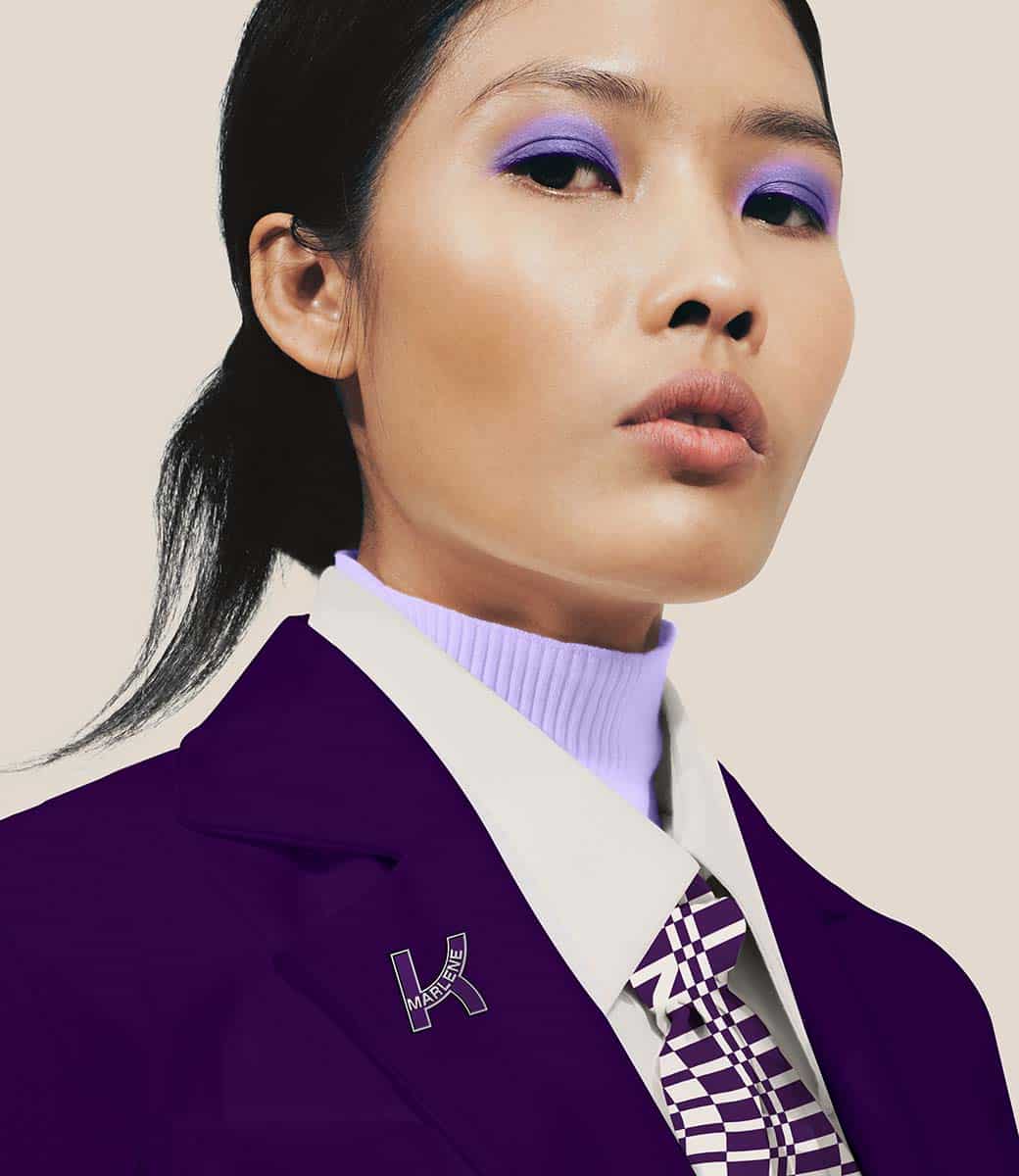 Ein Model blickt direkt i. die Kamera. ihr lilafarbenes makeup passt zur lila uniform mit Kathrein logo