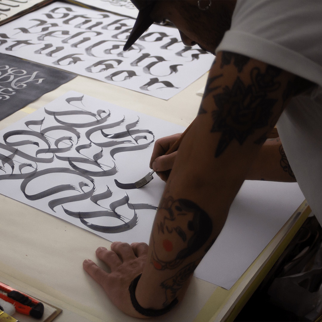 Ein Zeichner, der mit em Pinsel an einem Kalligrafie-Poster arbeitet