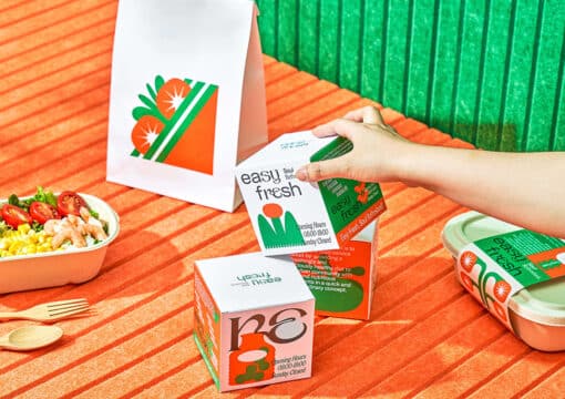 Eine hand hebt eine würfelförmige Verpackung von einem orangefarbenen Tisch