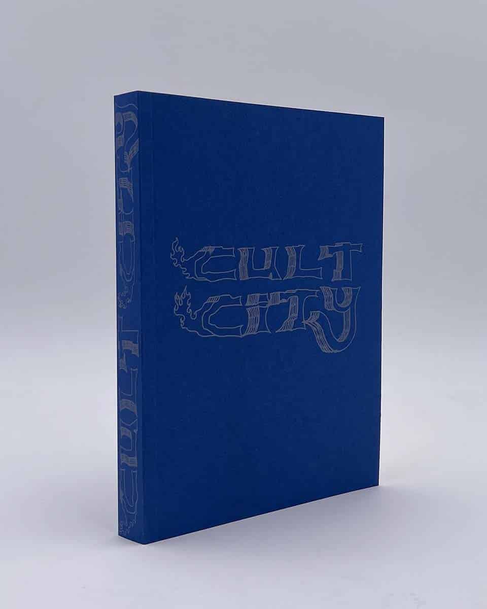 Ein blau gebundenes Buch mit dem handgezeichneten Titel »Cult City«