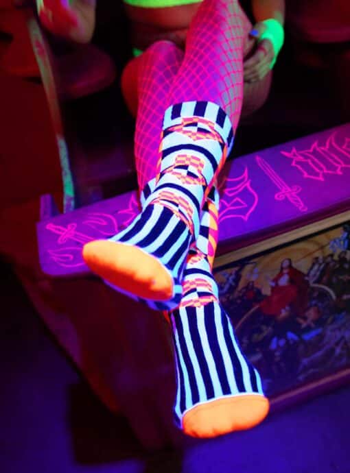 Zwei übereinandergeschlagene Füße mit orange leuchtenden Socken