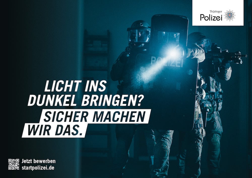 Recruitingkampagne für die Thüringer Polizei: Beamt:innen in Schutzausrüstung und Taschenlampen in einem dunklen Raum. Zu lesen: »Licht ins Dunkel bringen? Sicher machen wir das.«