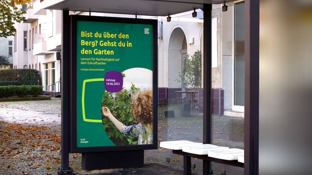 Neues Corporate Design für Erlangen: Plakat für einen Infotag im neuen Visual Design an einer Bushaltestelle