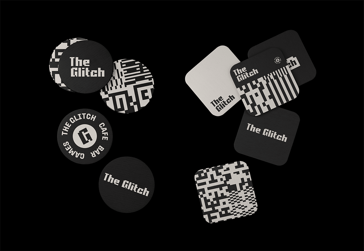 Runde und quadratische Untersetzer mit den verpixelten Glitch Logo und schwarz-weißem Pattern liegen auf schwarzem Grund