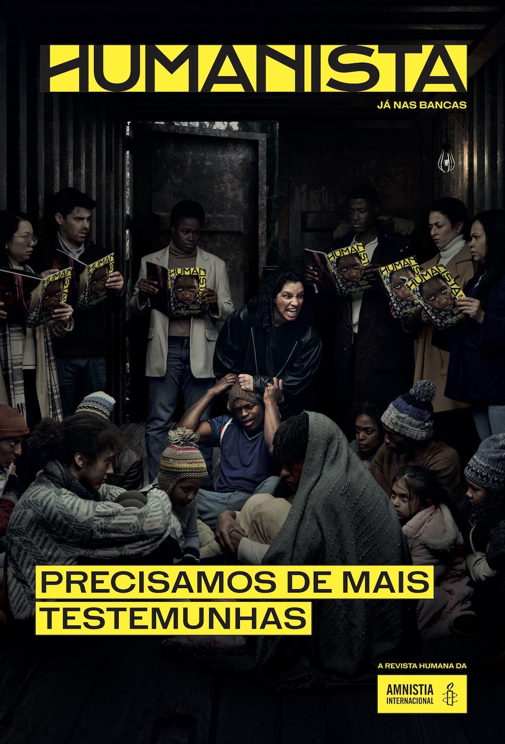 Kampagne für das neue Amnesty International Magazin Humanista: Ein Foto von einem dunklen Raum. Auf dem Boden sitzen mehrere Menschen in Decken und Mützen gehüllt. Eine Person in der Mitte zieht an der Mütze einer anderen Person und schreit. An den Wänden lehnen mehrere Personen, die das Humanists-Magazin lesen.