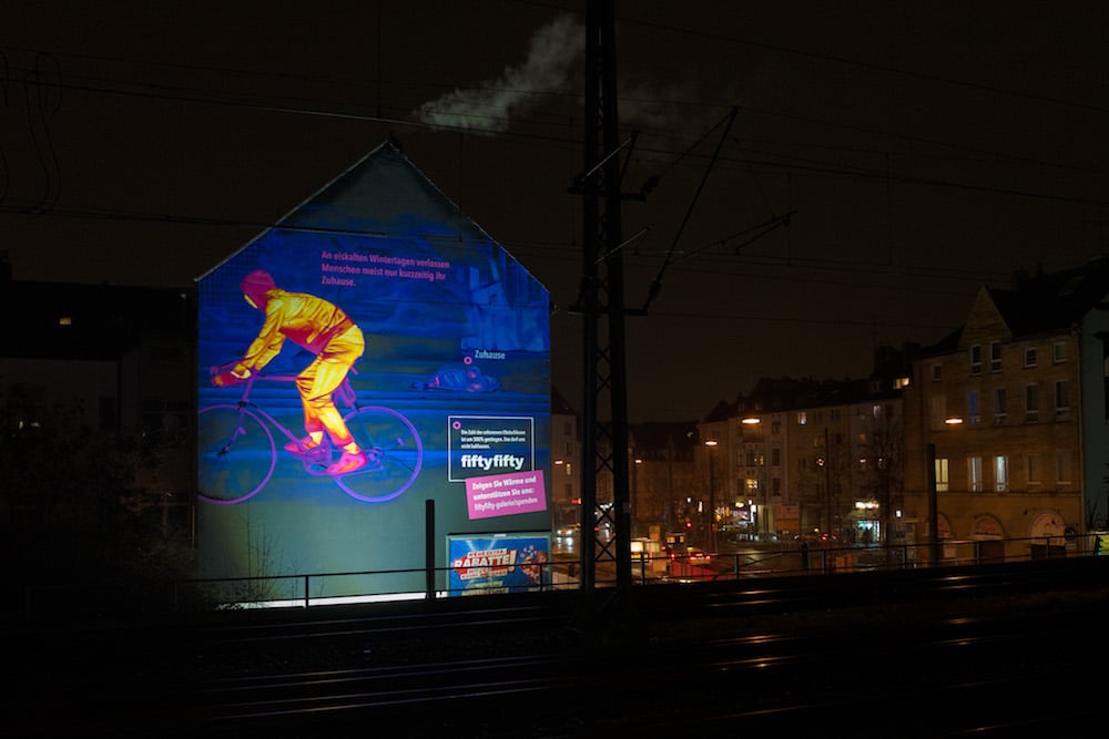 Kampagne »Winter in Deutschland« von fiftyfifty. Hauswand mit Wärmebild, nachts (Fahrradfahrer:in)
