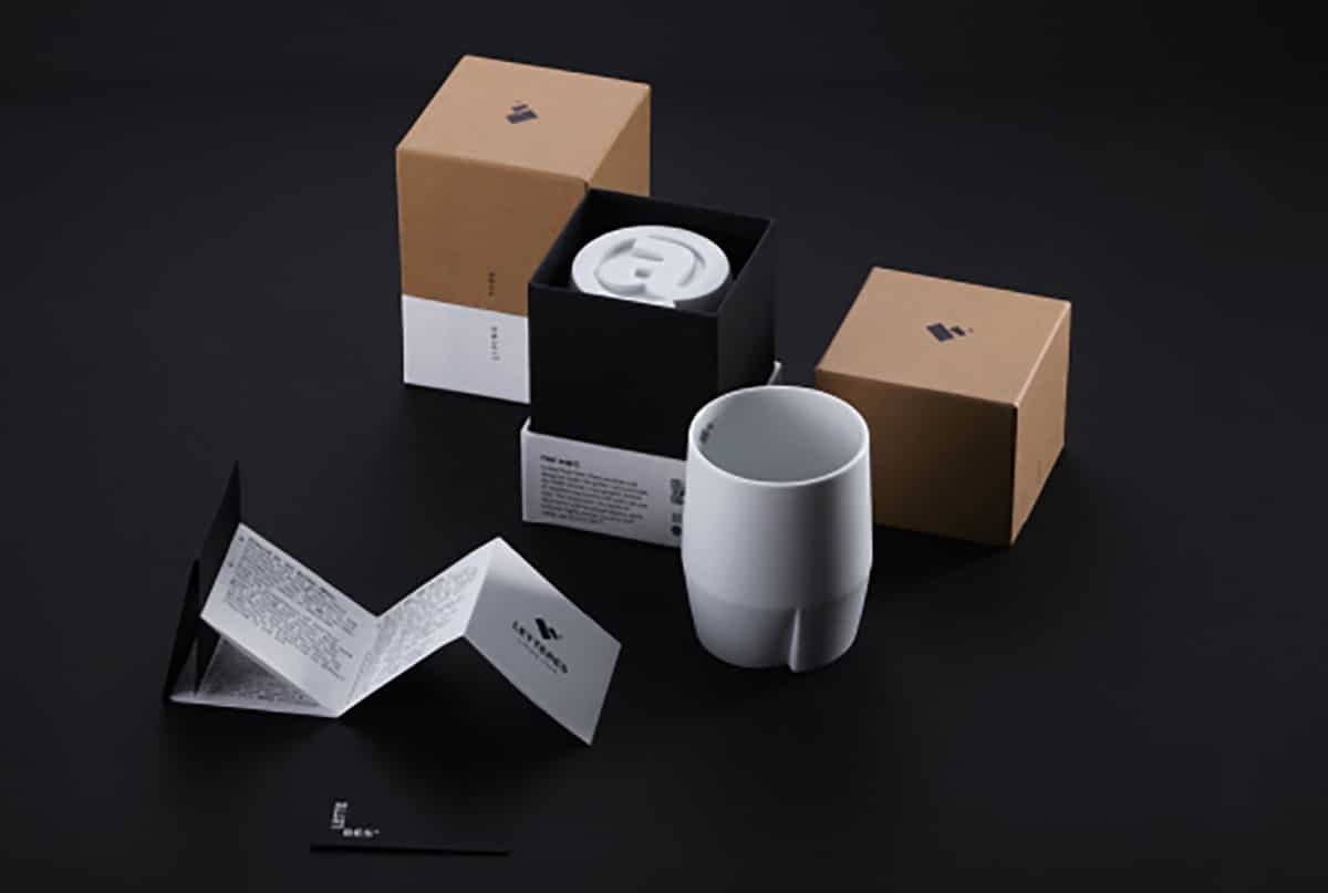 Eine Übersicht des Becher-Paketes, in dem ein weißer Keramikbecher, eine Falttbroschöre und ein aus recyceltem Naturpapier hergestelltes Packaging enthalten sind