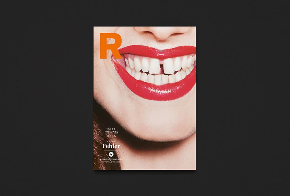 Die Rückseite des Realitäten-Magazins. Ein Foto von dem knallrot geschminkten Mund einer lachenden Frau mit einer Zahnlücken zwischen den beiden Vorderzähnen. In der Ecke oben links ein orangenes R