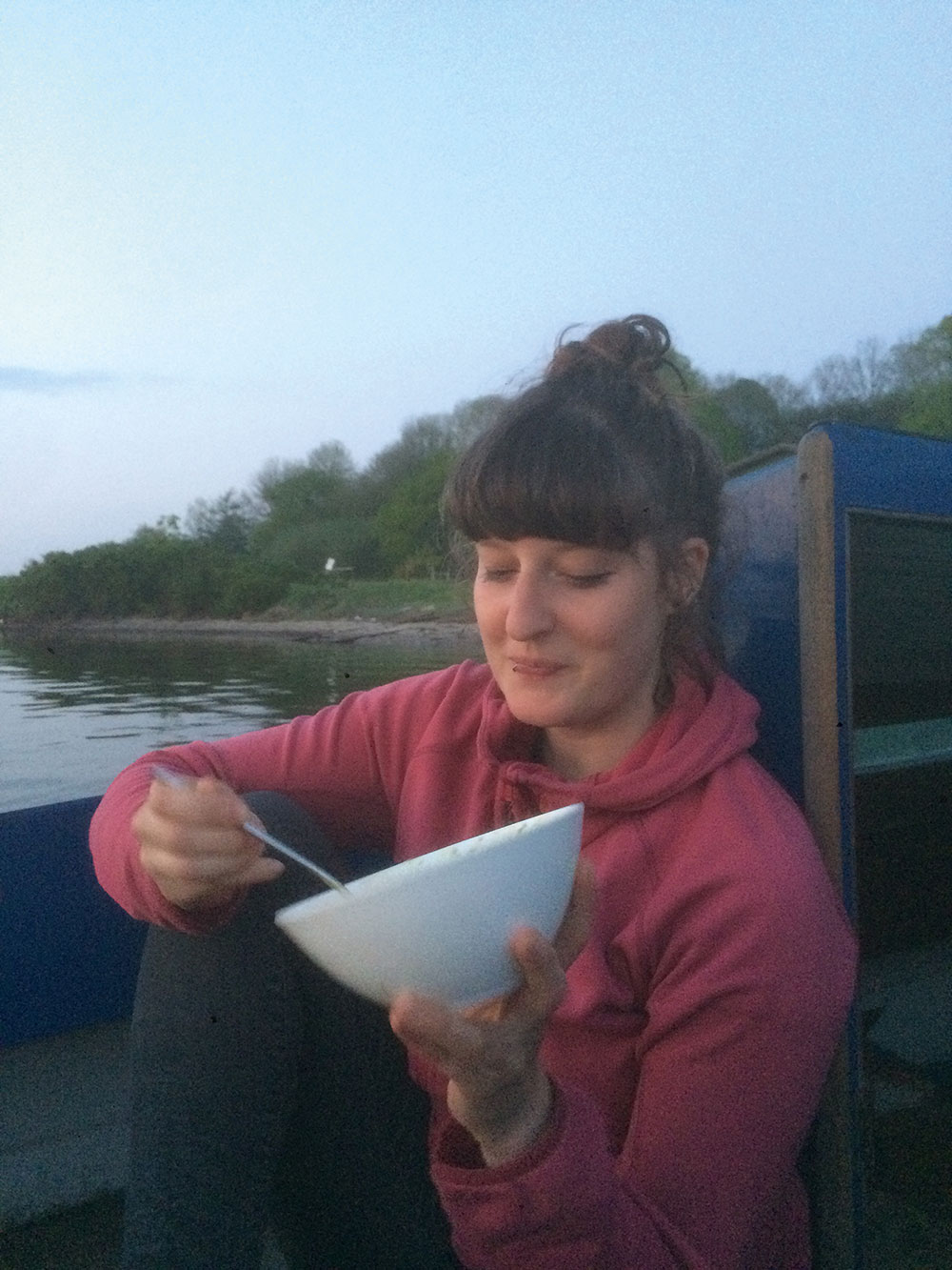 Ann Eckert sitzt entspannt auf einem Boot und isst Müsli aus einer Schüssel