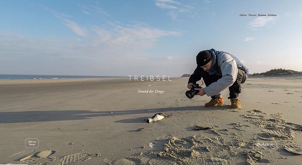 Thiemo Frömberg hockt am Strand und fotografiert einen verendeten Seevogel. 