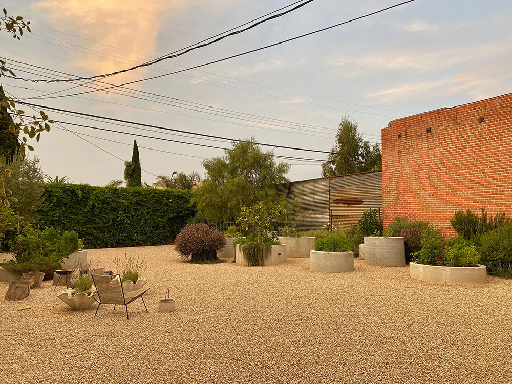 Steingarten in abendlichem Licht mit bepflanzten Betonbeeten