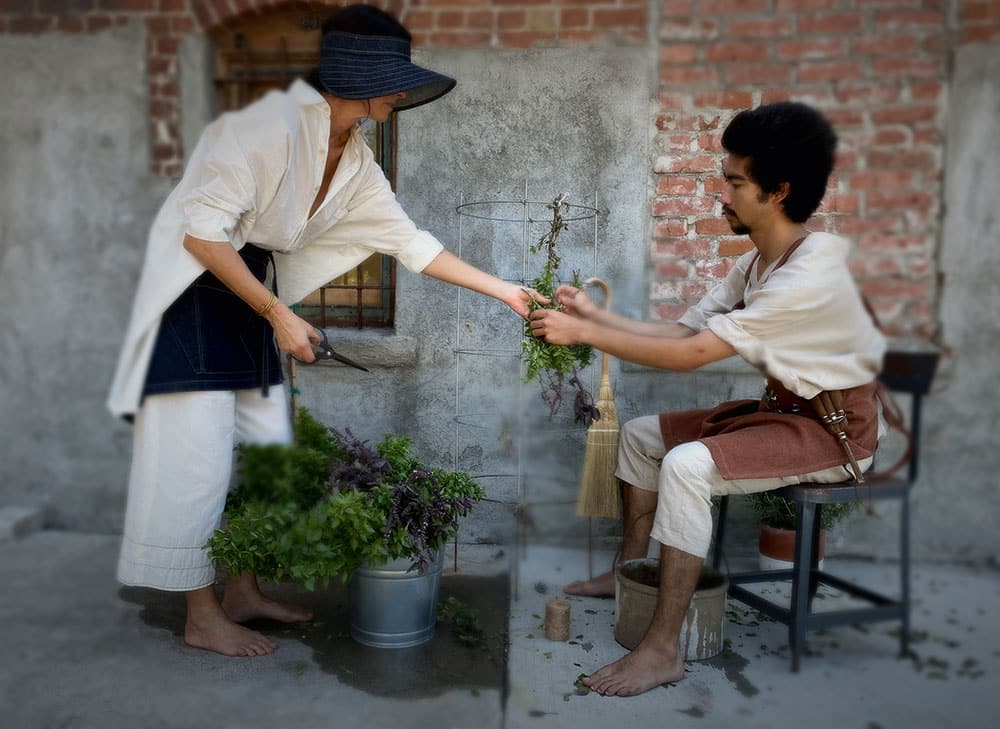 Filmstill aus dem Imagefilm von Flora Animalia in dem eine Person einer anderen ein Bund Kräuter reicht.