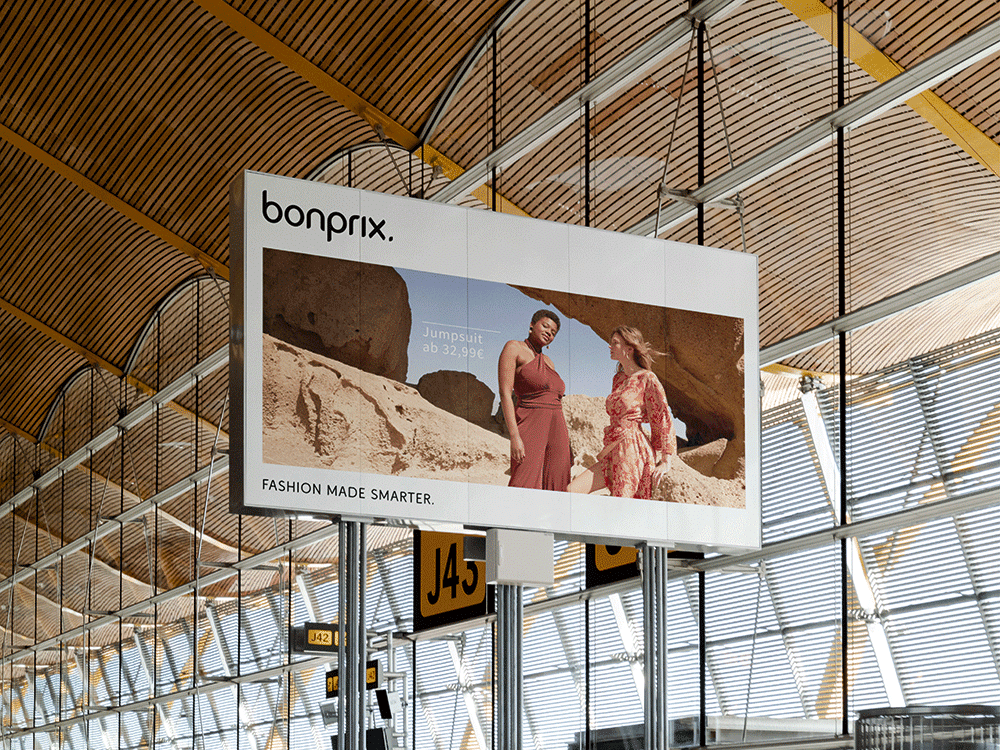 Großes Billboard von bonprix im neuen Design in einer Flughafen-Abflughalle