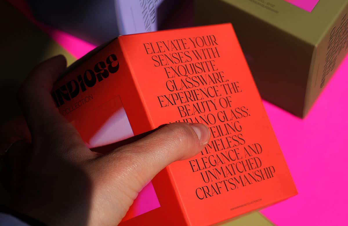 Eine Hand hält eine rotes Packaging mit versaler Typografie auf der Seite