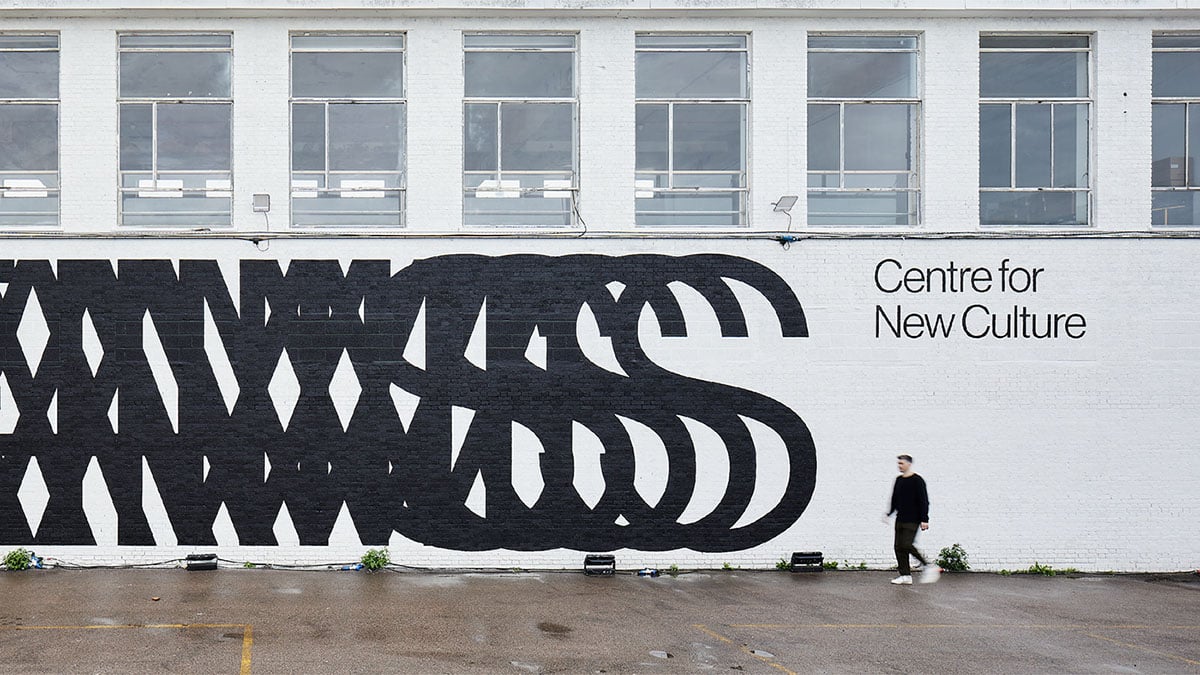 Eine Außenwand mit einem riesigen schwarzen Schriftzug aus einenander überlagernden Buchstaben