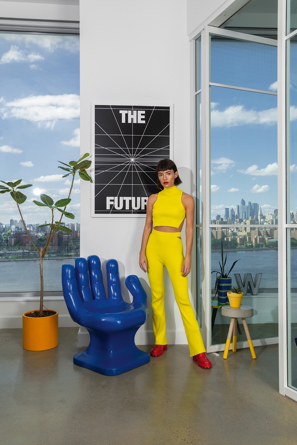 Portrait of Jessica Walsh in the studio next to a giant blue hand chair