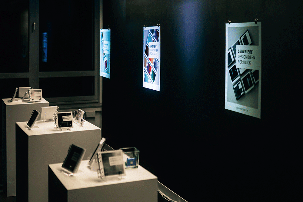 Ausstellungsansicht der Ausstellung von Maya Schürmann mit Ringbüchlein auf Podesten und Plakaten an der Wand