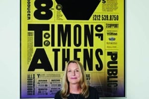 Paula Scher steht vor einem gelben typografisch gestalteten Poster