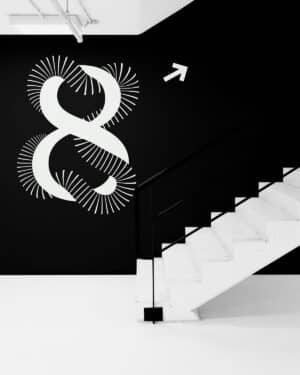 ein Treppenaufgang mit einer schwarzen wand daneben, auf der ein überdimensionales Leitsystem den achten stock zeigt