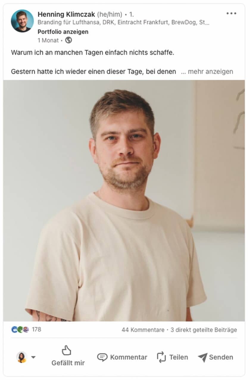  Das Foto zeigt einen Mann mit kurzen Haaren und einem leichtem Bart, der direkt in die Kamera blickt und einen neutralen Gesichtsausdruck hat. Er trägt ein einfaches, hellbeiges T-Shirt und steht vor einem unscharfen Hintergrund, der wie eine helle Wand erscheint. Der Mann scheint in einem Innenraum zu sein, und das Licht auf seinem Gesicht wirkt weich und natürlich.