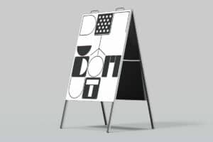 Eine dreidimensionale Darstellung eines Sandwich-Board-Werbeschildes mit abstraktem, schwarz-weißem Design, das geometrische Formen und Muster zeigt, auf einem einfarbigen, grauen Hintergrund.