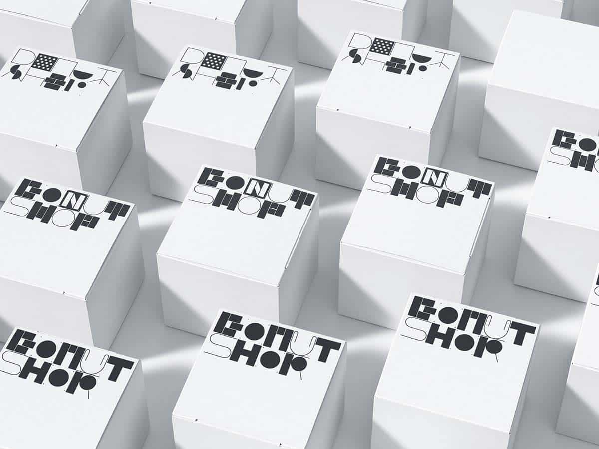 Mehrere weiße Würfel in einer 3D-Darstellung, die alle mit dem gleichen schwarz-weißen Muster bedruckt sind. Jeder Würfel zeigt ein Design, das aus geometrischen Formen und den Buchstaben, die 'DONUT SHOP' bilden, zusammengesetzt ist.