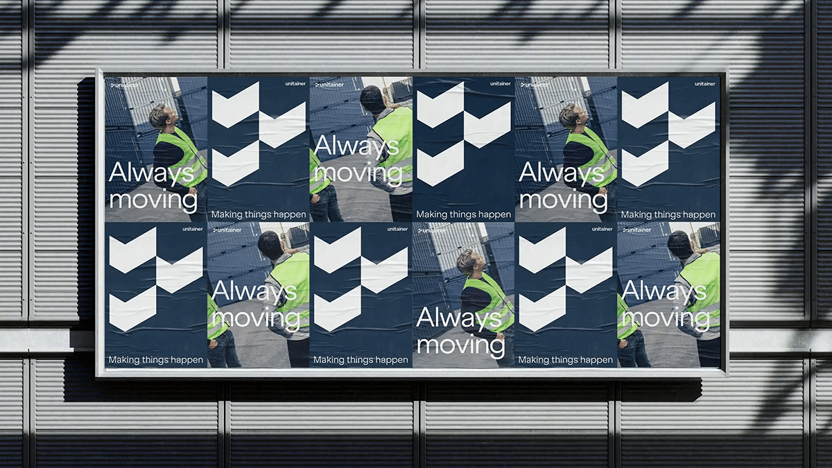 Werbeplakate mit dem Motto "Always moving" und "Making things happen", montiert an einer Außenfassade, wobei zwei Arbeiter in Sicherheitskleidung im Vordergrund zu sehen sind.