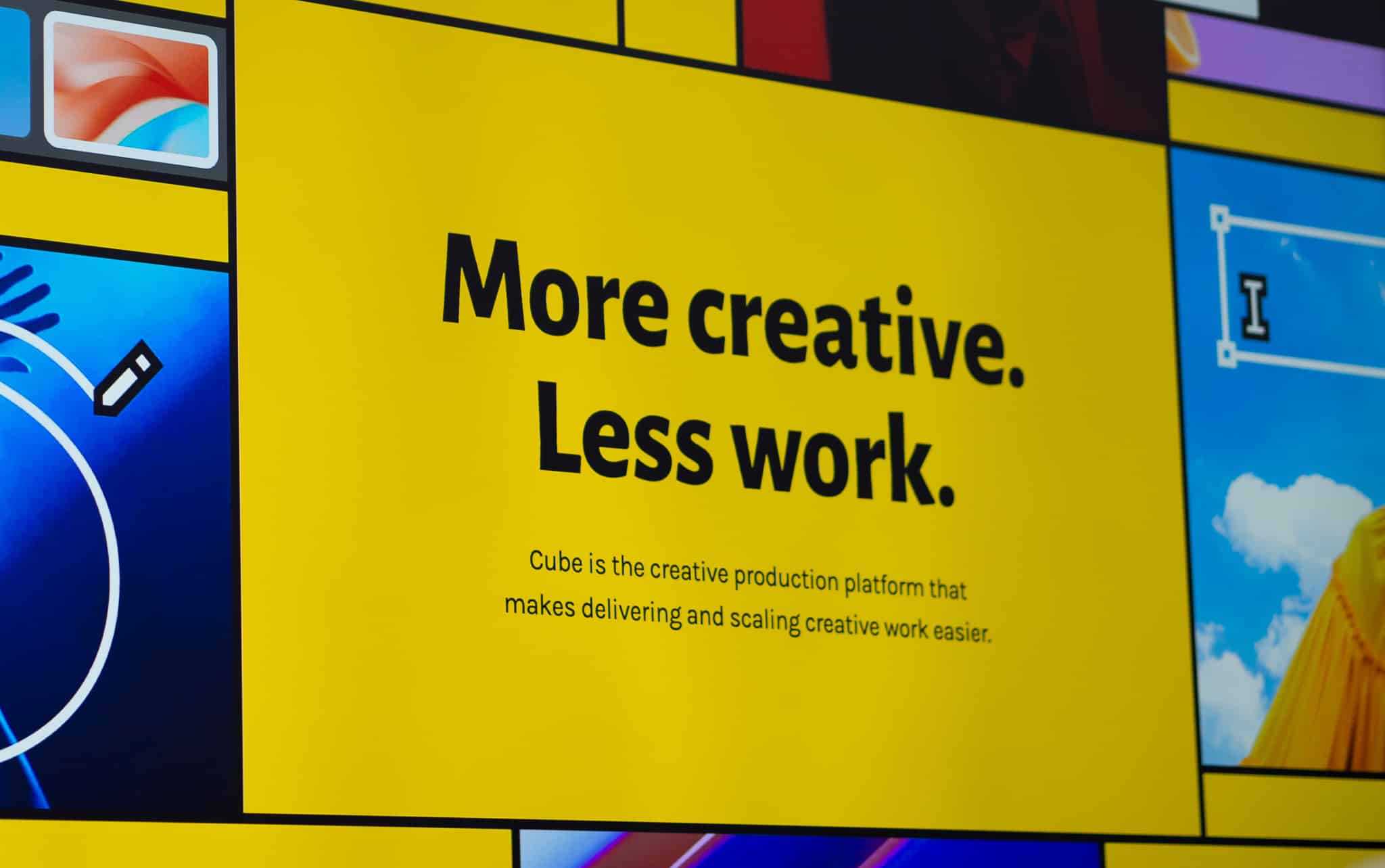 Ein gelbes Plakat mit der Aufschrift "More creative. Less work. Cube is the creative production platform that makes delivering and scaling creative work easier." Es sind verschiedene bunte Bilder rund um das Plakat zu sehen.