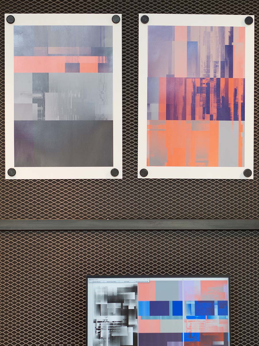 Zwei abstrakte Kunstwerke mit geometrischen Mustern in Grautönen und leuchtenden Orangetönen. Darunter ist ein Bildschirm, der eine ähnliche abstrakte Grafik zeigt, auf einem Gitterhintergrund montiert.