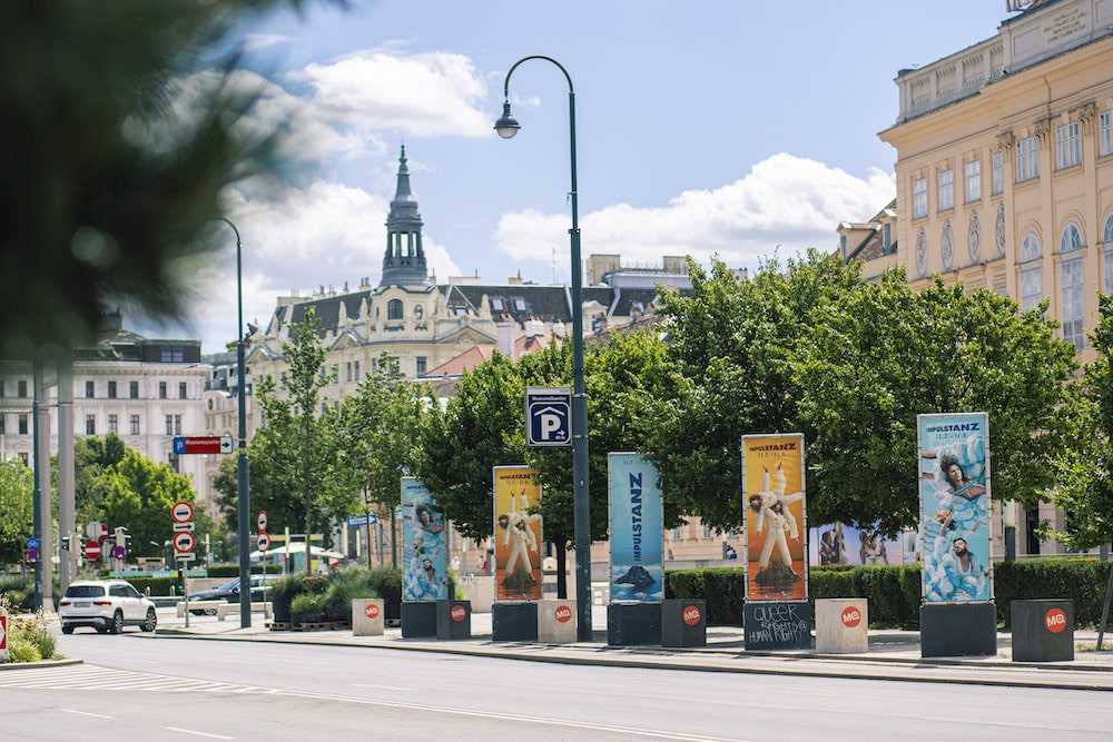 Diverse Kampagnen-Plakate für das Tanzfestivals ImPulsTanz, von der KI entwickelte Motive, auf Stehlen am Straßenrand