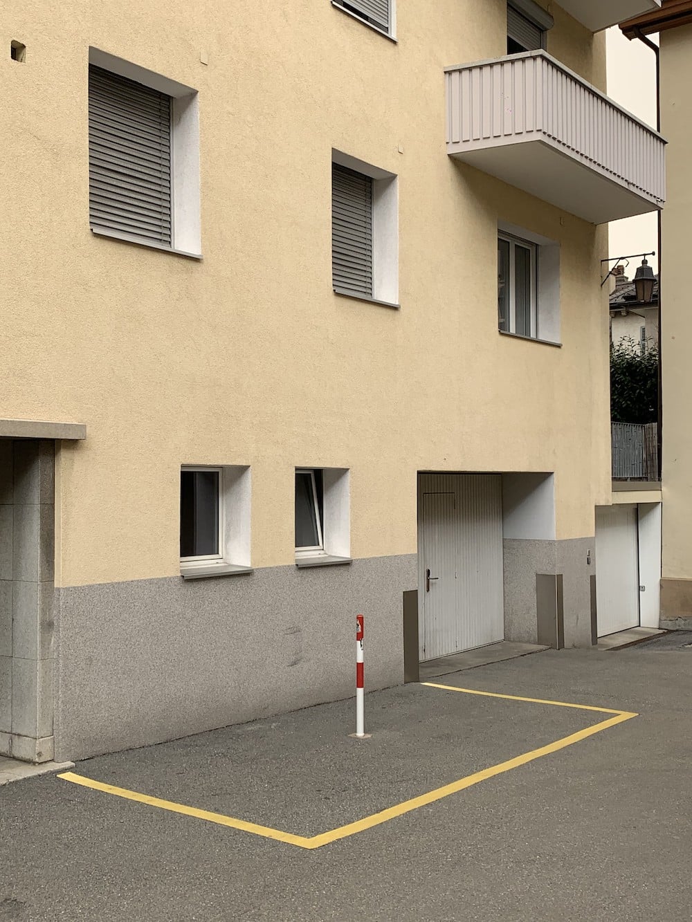 Im Düsseldorfer Kunstmuseum K21 zeigt der Schauspieler Lars Eidinger mit was für einem offenen und interessierten Blick er durchs Leben geht. Hier: Tristes Wohnhaus mit rotweißem Polder in abgetrenntem Parkplatz