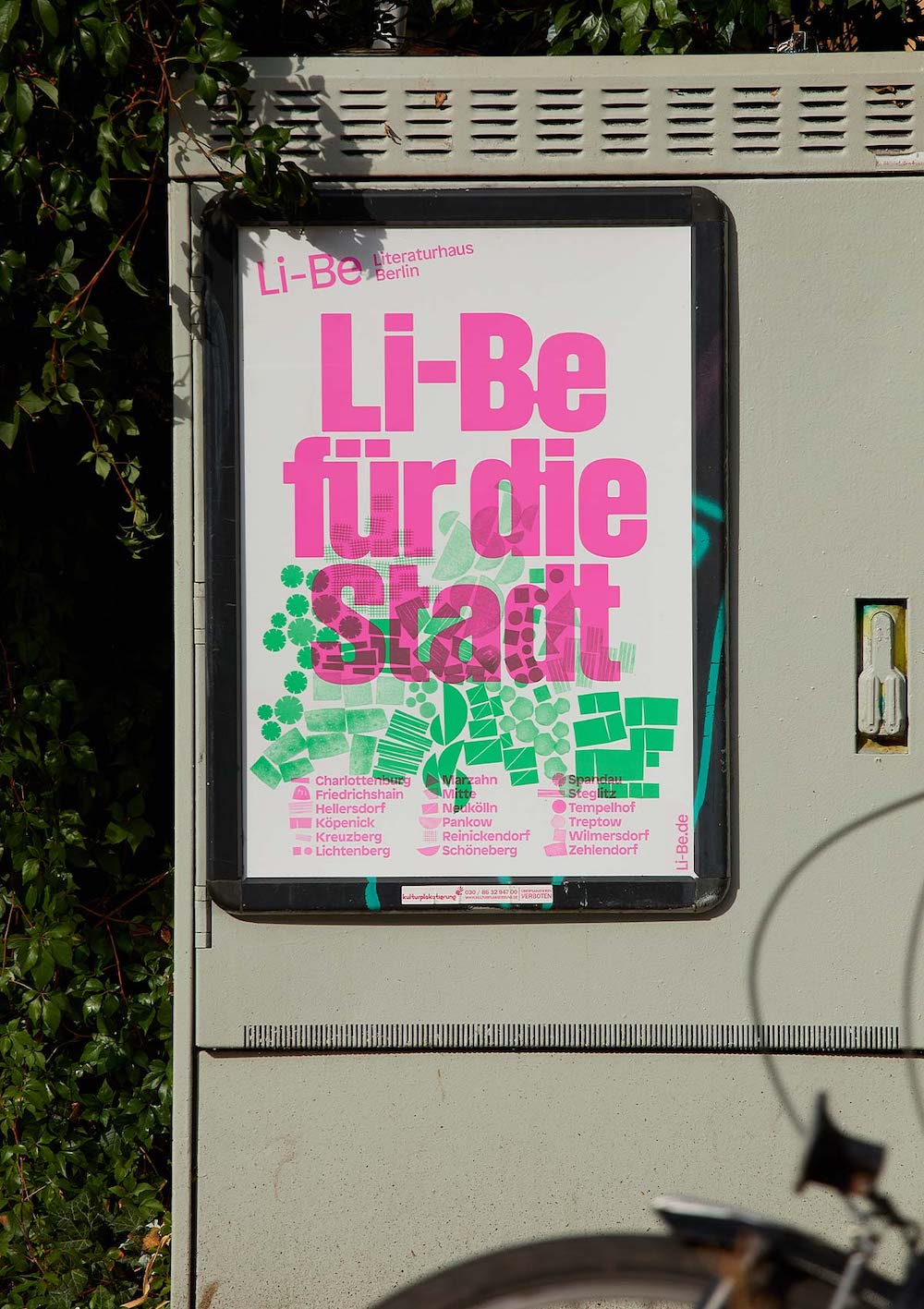 Pink und lilafarbenes Plakat für Li-Be für die Stadt, das an Stromkasten hängt