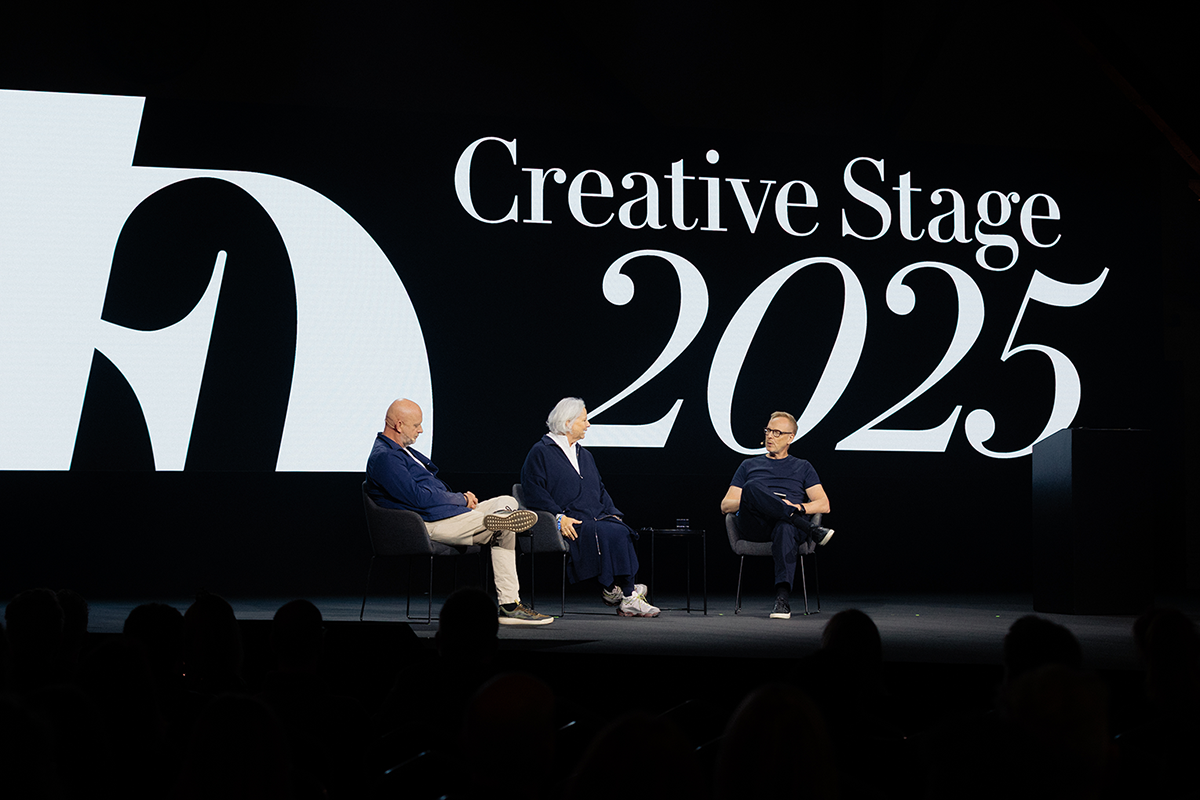 Drei Personen sitzen auf einer Bühne und diskutieren im Rahmen der „Creative Stage 2025“, mit großem Logo im Hintergrund.