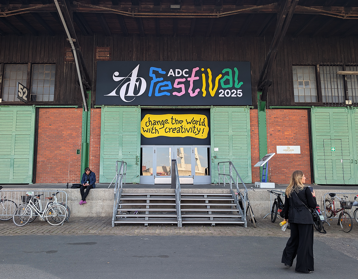 Außenansicht des Eingangs zum „ADC Festival 2025“ mit farbenfrohem Festival-Schriftzug und dem Motto „Change the world with creativity!“